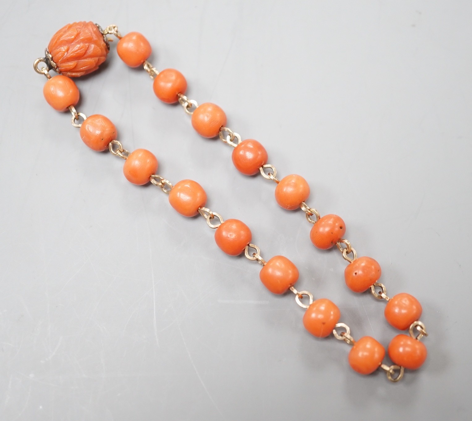 A yellow metal and coral bead bracelet, with carved coral bead clasp, 19.5cm.